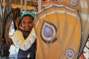 A student riding a butterfly on a carousel.
