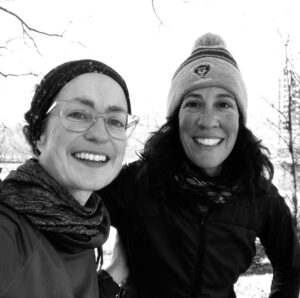 A black and white smiling selfie of Jody, pictured left, and Kristin, pictured right, as they take a moment on a snowy training run.